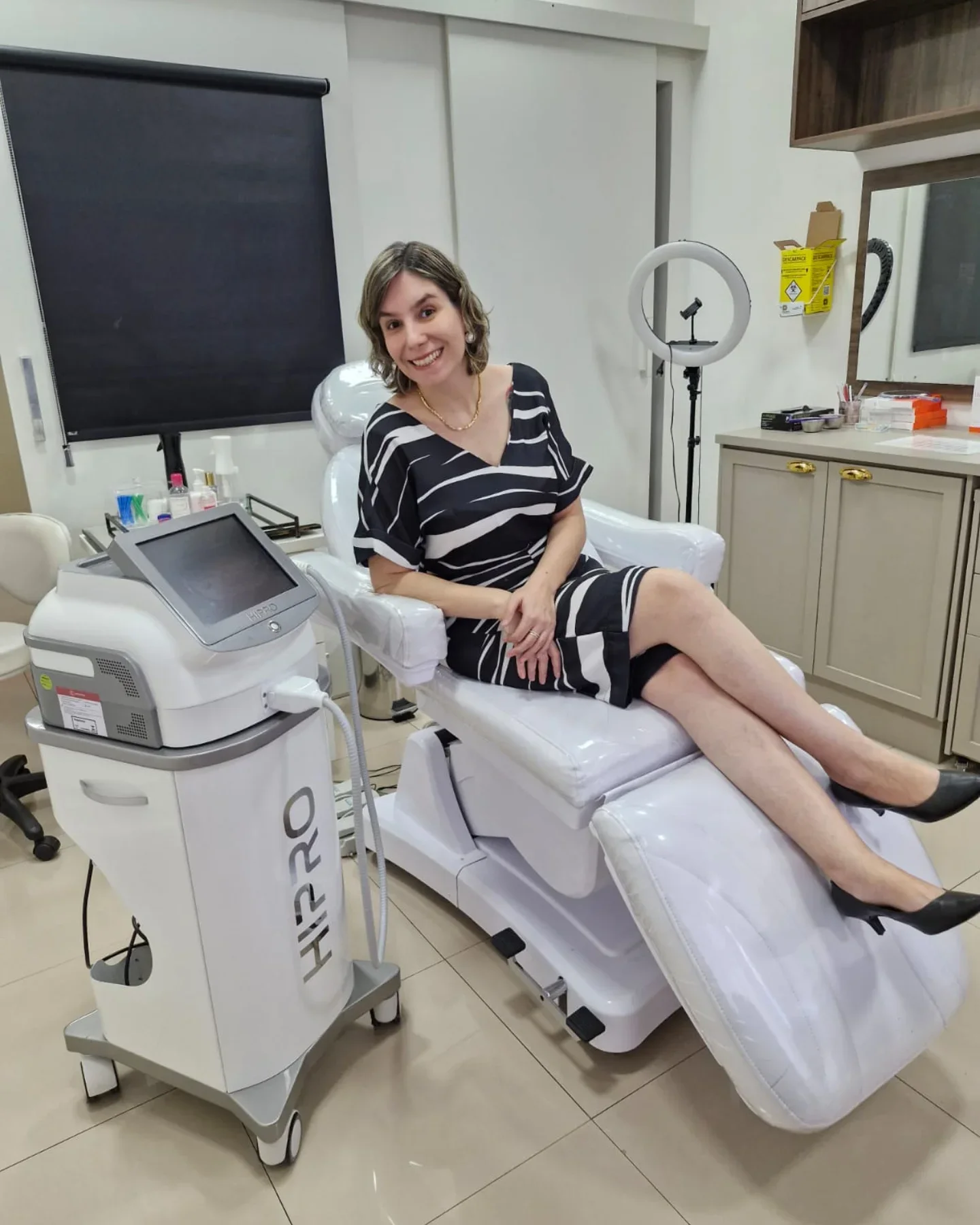 Dra. Eveline Saad sentada na poltrona de atendimento, na sala com armários de madeira